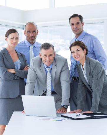 Business team working happily together on laptop in the office Business team working happily together on laptop in the office
